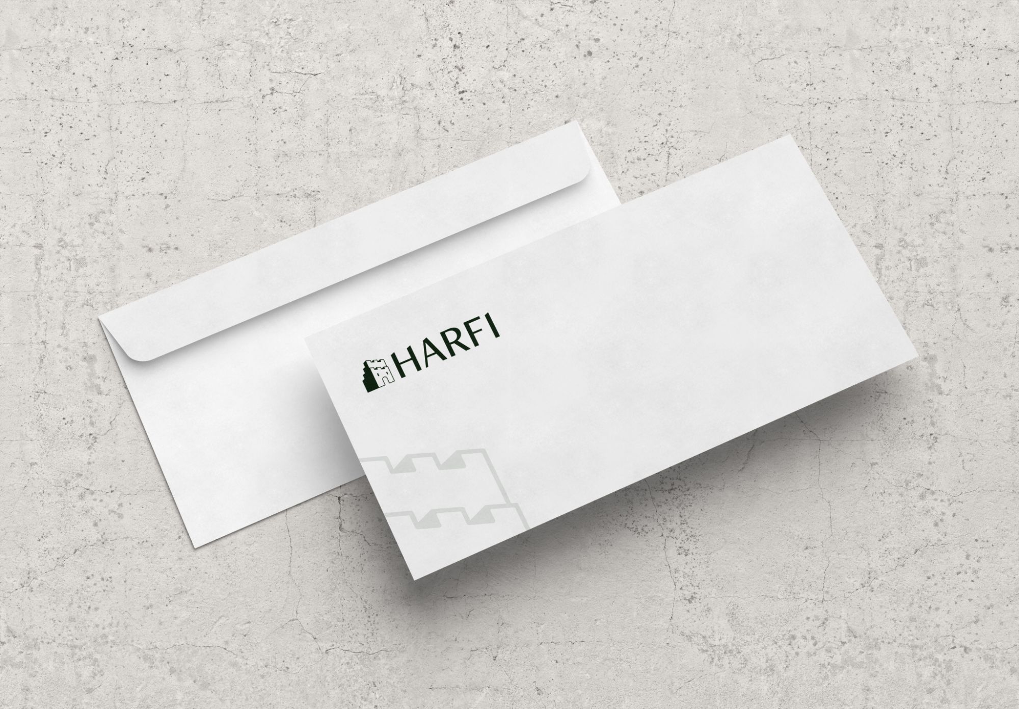 Mockup van twee enveloppen van Harfi op een betonnen ondergrond